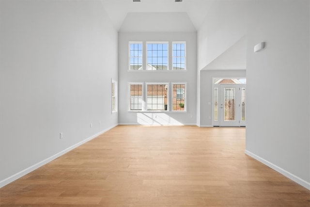 unfurnished living room featuring high vaulted ceiling and light hardwood / wood-style floors