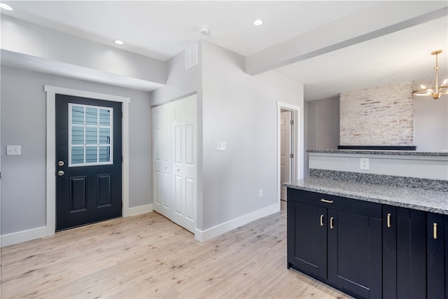 kitchen with a chandelier, light hardwood / wood-style flooring, decorative light fixtures, and light stone counters