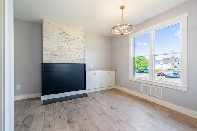 unfurnished room featuring a notable chandelier and light hardwood / wood-style flooring