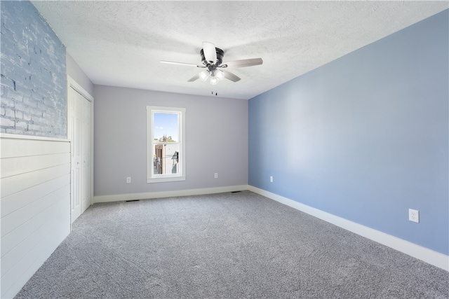 unfurnished room with a textured ceiling, ceiling fan, and carpet floors