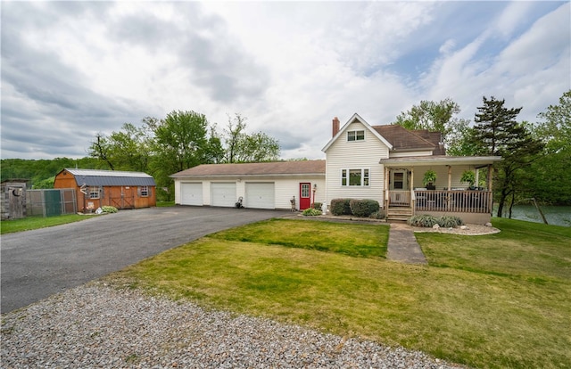 view of front facade with covered porch, an outdoor structure, a garage, and a front yard