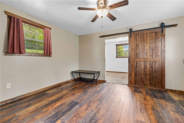 unfurnished room featuring wood-type flooring, ceiling fan, and a barn door