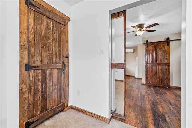 interior space featuring a wall mounted AC, ceiling fan, a barn door, and dark wood-type flooring