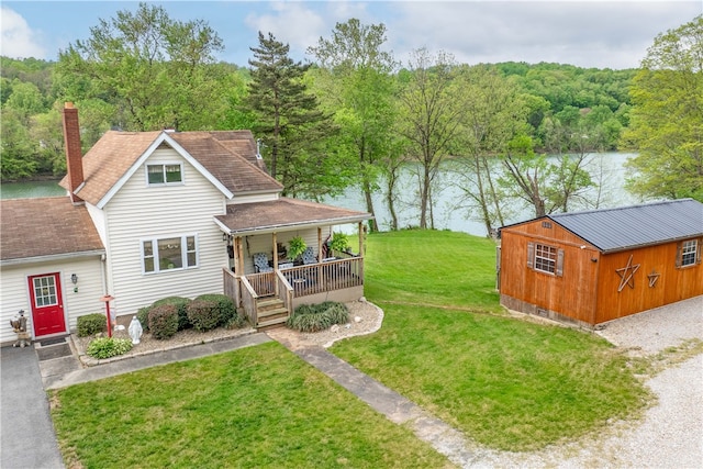 view of yard with covered porch, an outdoor structure, and a water view