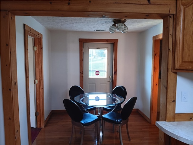 dining space with a textured ceiling and dark hardwood / wood-style flooring