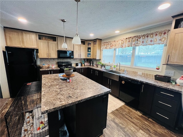 kitchen featuring hanging light fixtures, black appliances, light brown cabinetry, a center island, and light wood-type flooring