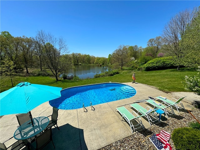 view of swimming pool featuring a patio area, a water view, and a yard