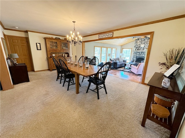 dining area with a stone fireplace, crown molding, vaulted ceiling, light wood-type flooring, and a notable chandelier