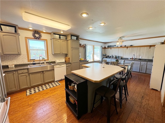 kitchen featuring sink, light hardwood / wood-style floors, crown molding, and white appliances