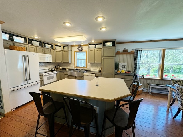 kitchen featuring a center island, ornamental molding, white appliances, dark hardwood / wood-style floors, and a breakfast bar