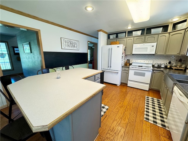 kitchen with crown molding, white appliances, light wood-type flooring, backsplash, and a breakfast bar area