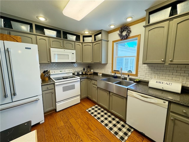 kitchen featuring tasteful backsplash, white appliances, ornamental molding, hardwood / wood-style flooring, and sink