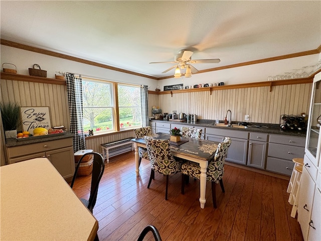 dining space with dark hardwood / wood-style floors, ceiling fan, sink, and ornamental molding