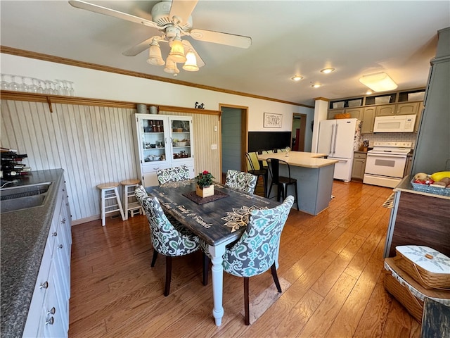 dining space featuring ceiling fan, sink, ornamental molding, and light hardwood / wood-style floors