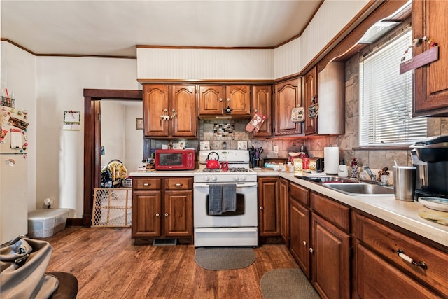 kitchen featuring built in microwave, sink, dark wood-type flooring, and gas range gas stove