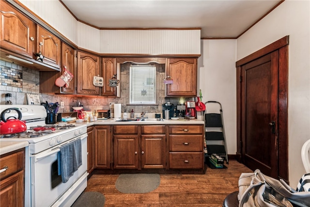 kitchen featuring white gas range, sink, dark wood-type flooring, and backsplash