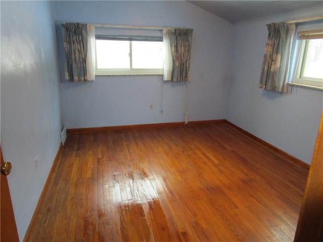 spare room with hardwood / wood-style flooring, plenty of natural light, and lofted ceiling