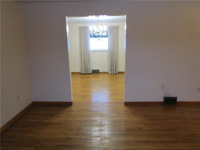 unfurnished room with dark hardwood / wood-style flooring and a chandelier