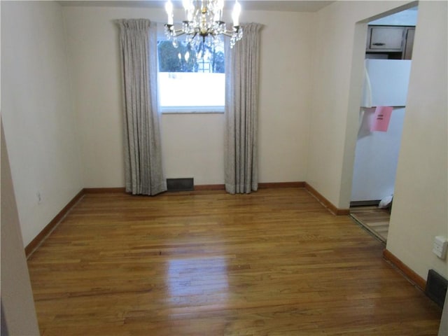 unfurnished room featuring an inviting chandelier and wood-type flooring