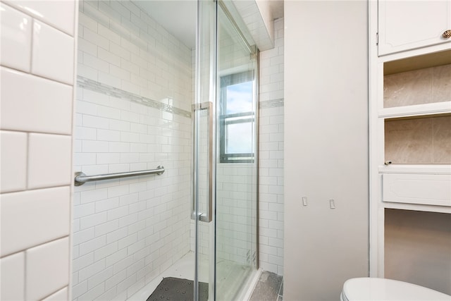 bathroom with a shower with door and toilet