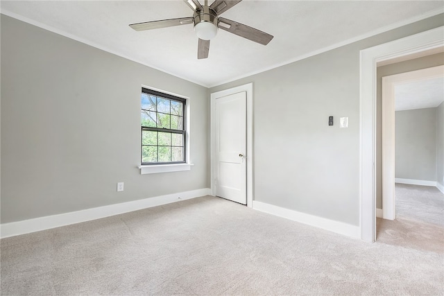 carpeted empty room featuring ceiling fan and crown molding