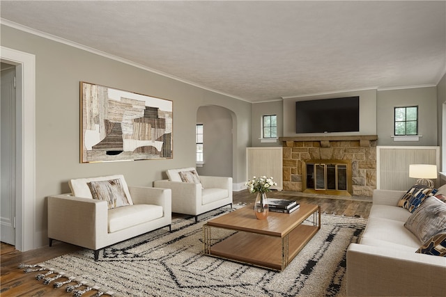 living room featuring ornamental molding, hardwood / wood-style floors, and a stone fireplace