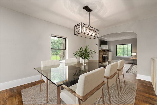 dining area featuring a stone fireplace and dark hardwood / wood-style floors