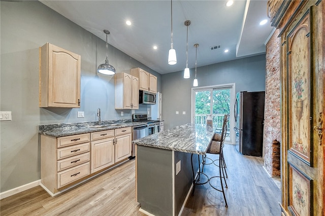 kitchen featuring light brown cabinetry, light hardwood / wood-style floors, stainless steel appliances, a center island, and pendant lighting