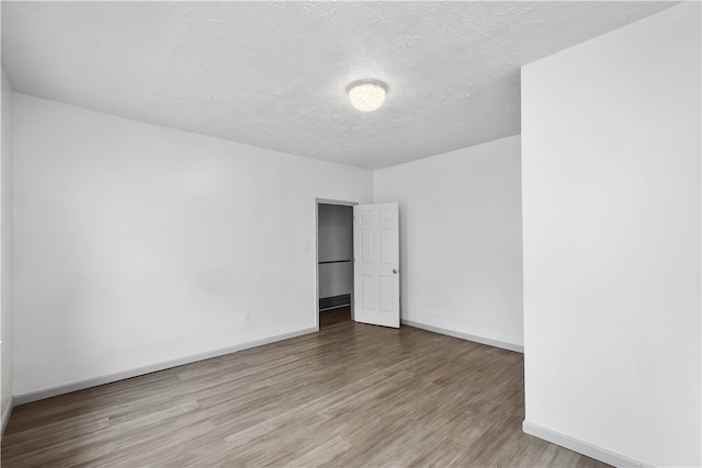 unfurnished room with hardwood / wood-style flooring and a textured ceiling