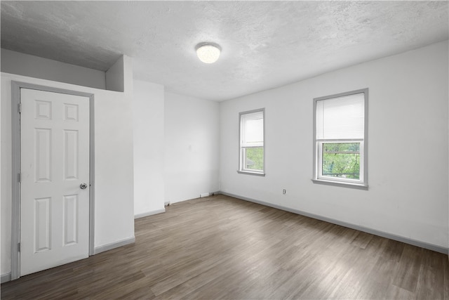 empty room with a textured ceiling and hardwood / wood-style flooring