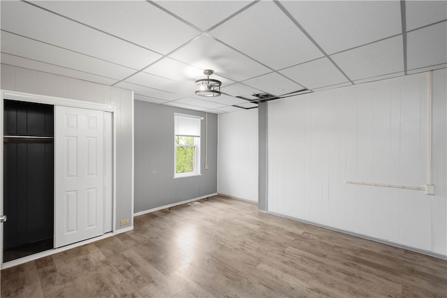 unfurnished bedroom featuring a closet, a drop ceiling, and hardwood / wood-style floors