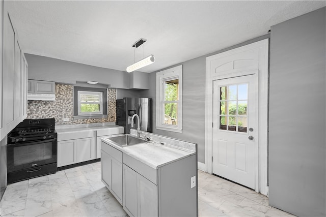 kitchen featuring a healthy amount of sunlight, gas stove, sink, and an island with sink