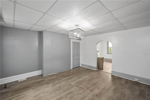 unfurnished room featuring wood-type flooring and a drop ceiling