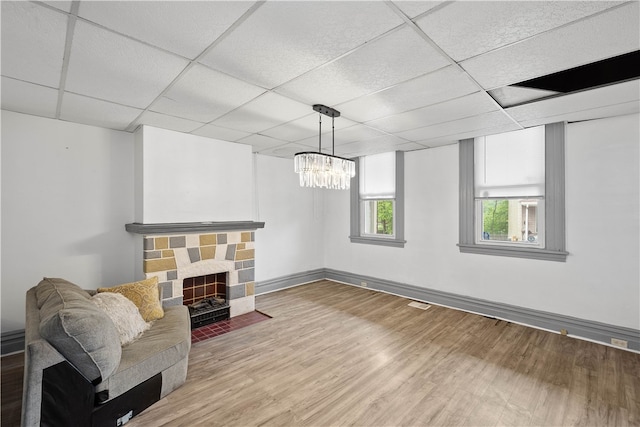 living room featuring a chandelier, a paneled ceiling, hardwood / wood-style floors, and a fireplace