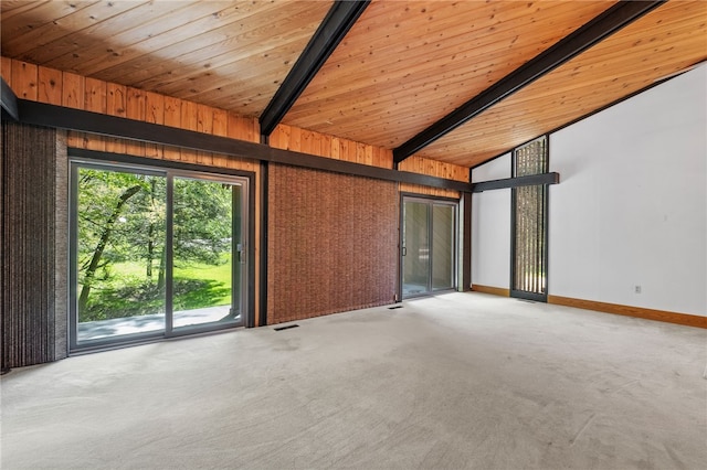 carpeted empty room with lofted ceiling with beams, wooden ceiling, and wood walls