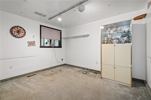 carpeted empty room featuring rail lighting