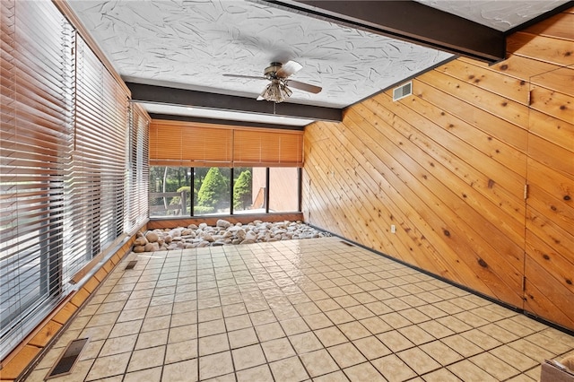 tiled empty room with beam ceiling and ceiling fan