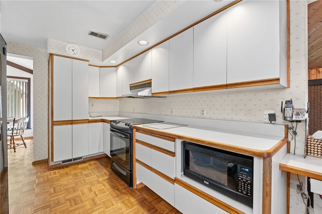 kitchen with light parquet floors, white cabinetry, wall chimney exhaust hood, and black appliances