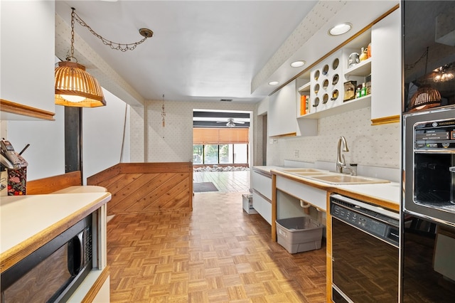 kitchen with pendant lighting, white cabinets, sink, dishwasher, and light parquet flooring