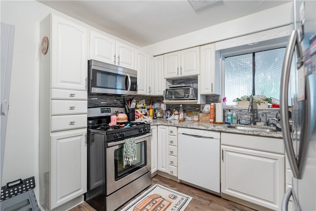 kitchen featuring white cabinets, dark hardwood / wood-style flooring, backsplash, appliances with stainless steel finishes, and sink