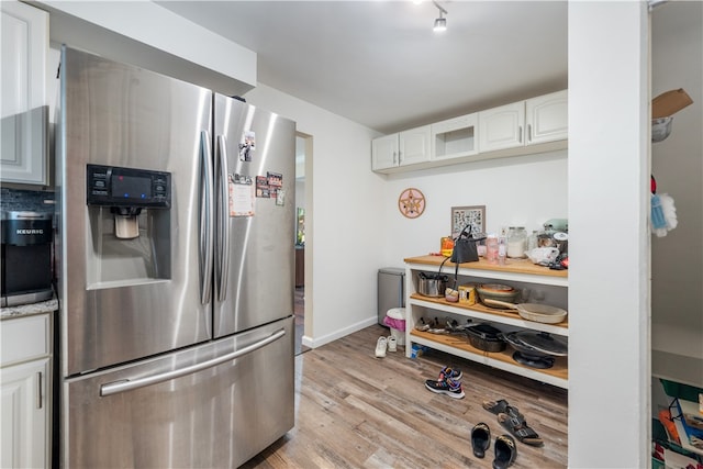 kitchen featuring rail lighting, light hardwood / wood-style flooring, white cabinets, and stainless steel fridge