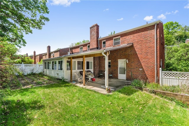 rear view of house featuring a lawn and a patio