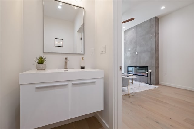 bathroom featuring wood-type flooring, a fireplace, vanity, and ceiling fan