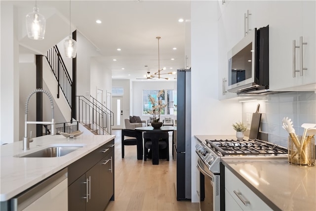 kitchen featuring backsplash, pendant lighting, light hardwood / wood-style floors, and stainless steel appliances