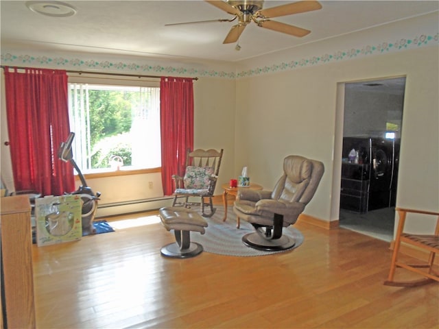 living area featuring baseboard heating, wood-type flooring, and ceiling fan