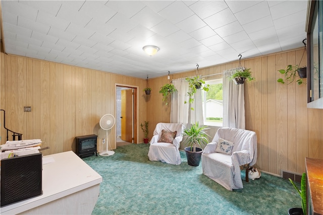 interior space featuring wooden walls, a wood stove, and carpet floors