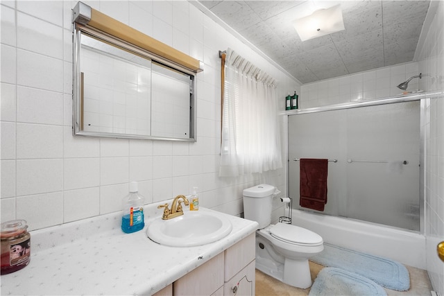 full bathroom with toilet, oversized vanity, tile walls, and shower / bath combination with glass door