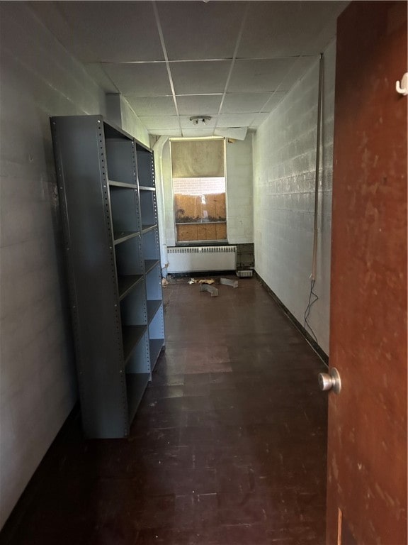 corridor with hardwood / wood-style flooring, radiator heating unit, and a paneled ceiling