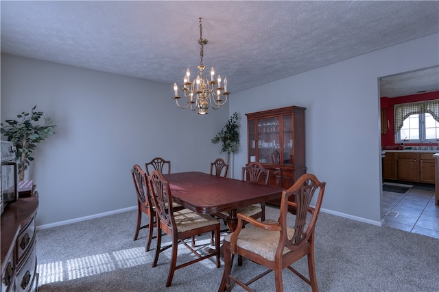 tiled dining room with sink, an inviting chandelier, and a textured ceiling