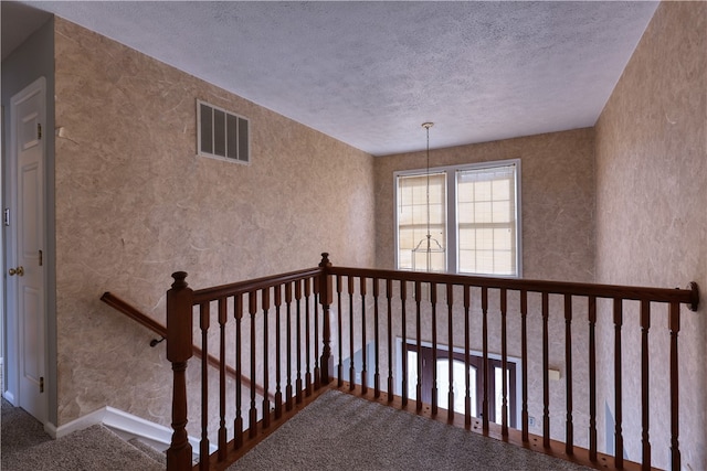 hallway featuring carpet flooring and a textured ceiling